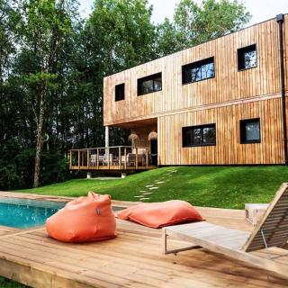 Construction moderne et confortable, le gîte est installé entre un petit bois et un champ. Grand jardin, terrasses, piscine et des arbres partout !
